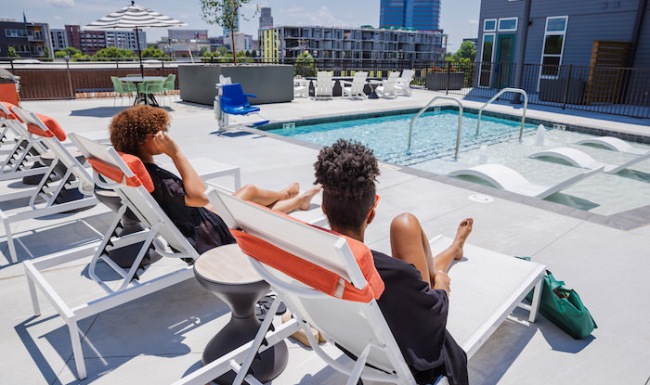 Large sparkling blue pool with a large deck and lounge chairs 
