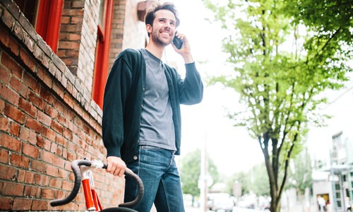 Neighborhood Walk Score Man on a neighborhood street next to bike talking on his phone and smiling